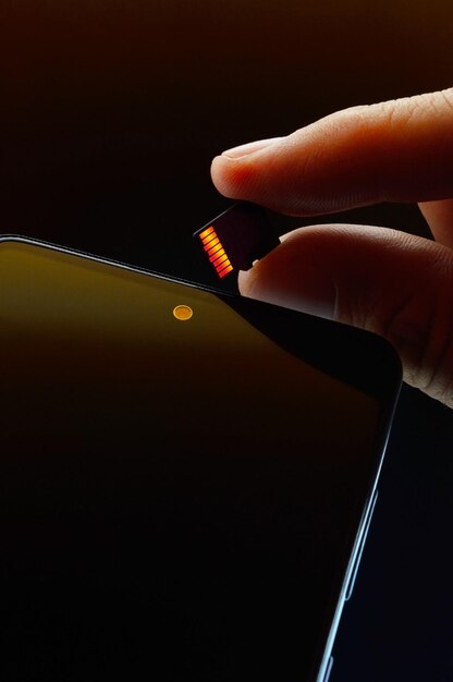 Выключенный смартфон и карта micro sd, удерживаемые человеческими пальцами