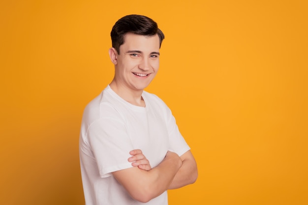 Turned photo of happy handsome man crossing hands isolated over yellow background