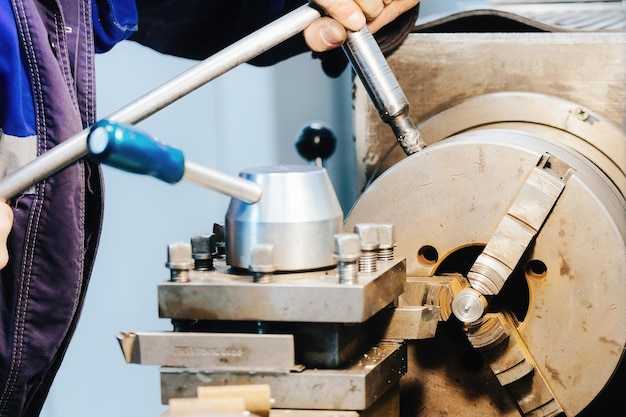 Turner hands and lathe closeup metal turner works at workplace in lathe shop