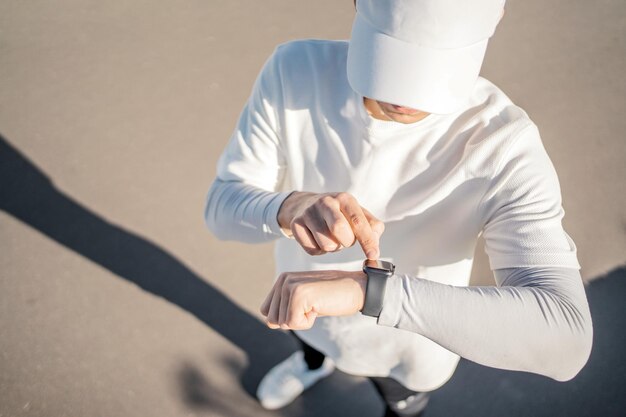 Turns on the smartwatch and the phone app the athlete runner is preparing for a running workout