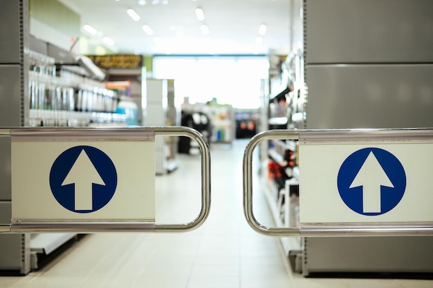 Turnstile wickets with blue entrance signs in a supermarket