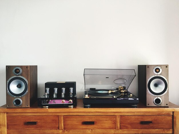 Photo turntable amidst speakers on table by white wall