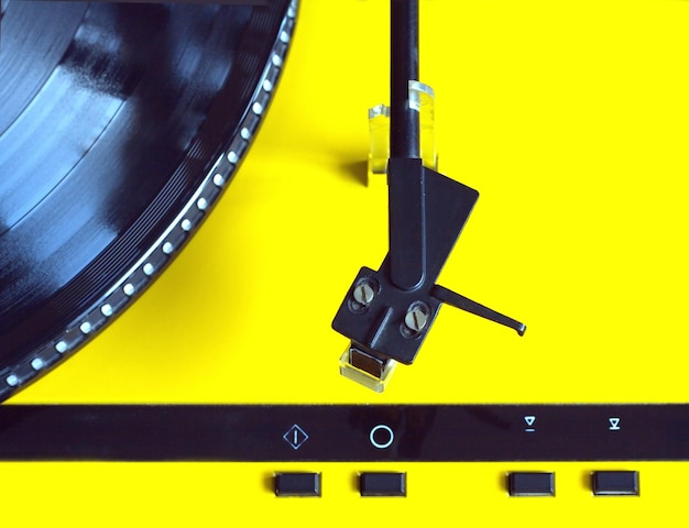 黄色のケースに入ったターンテーブル、黒いトーンアームと黒いコントロールボタンが付いており、ビニールレコードの再生にすぐに使用できます