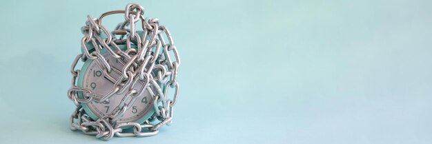 Turquoise alarm clock is wrapped in chrome chain closeup