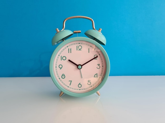 Turquoise alarm clock for ten o'clock on blue background