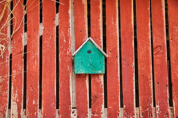 Фото Бирюзовый скворечник на выцветшем красном амбаре