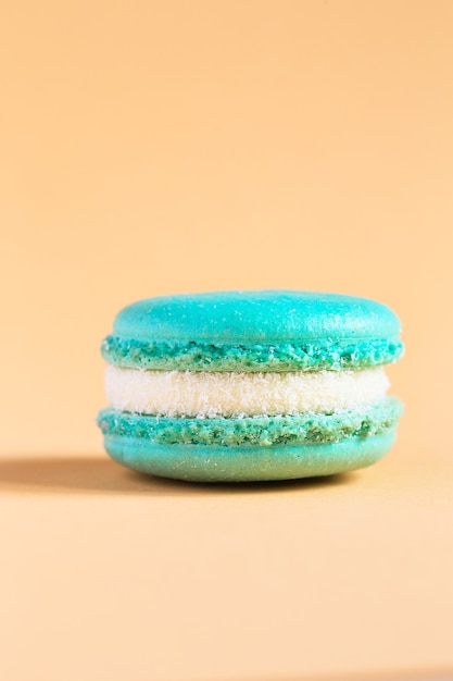 Turquoise Cake macaron or macaroon on yellow wall. colorful almond cookies. French macaroon 