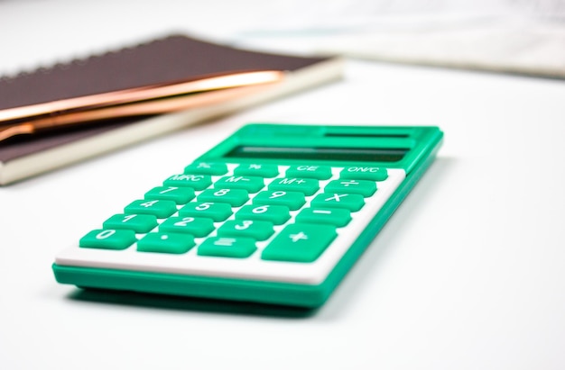 Turquoise calculator on a white table with documents Financial transactions cost calculation investment profit