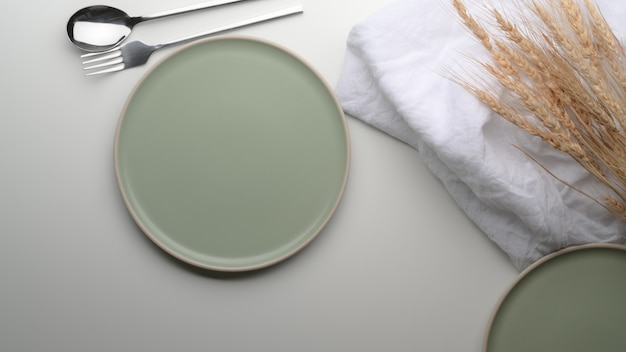  turquoise ceramic plates, silverware, napkin and golden wheat decorated on white dinning table