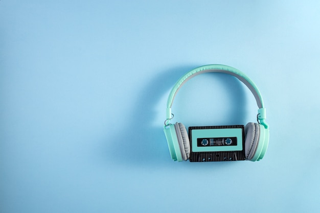 Turquoise headphones with audio cassette on a blue background. Music concept