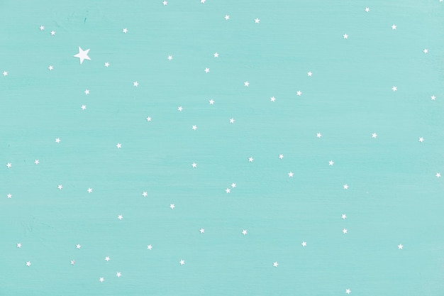 Turquoise houten achtergrond met kleine glanzende zilveren sterren