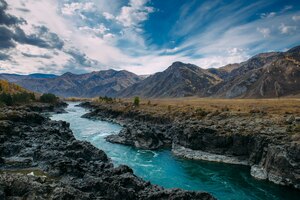 Turquoise katun rivier in kloof is omgeven door hoge bergen onder majestueuze herfsthemel. een stormachtige bergstroom loopt tussen rotsen - landschap van de altai-bergen, prachtige plekken van de planeet.