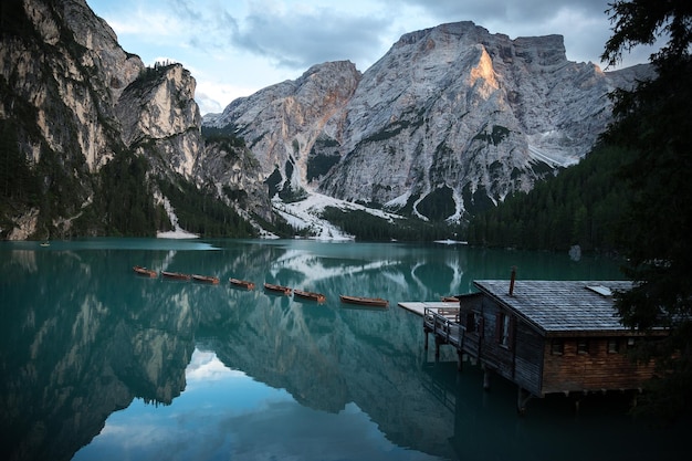 写真 水に反射したボートと小さな木造の家のあるターコイズブルーの湖の風景