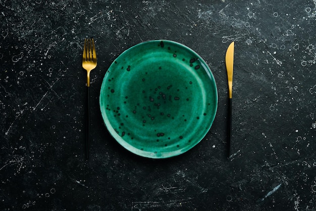 Turquoise plate and cutlery on a black stone background Top view Rustic style