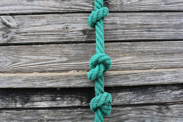 Turquoise rope with knots on a gray wooden surface