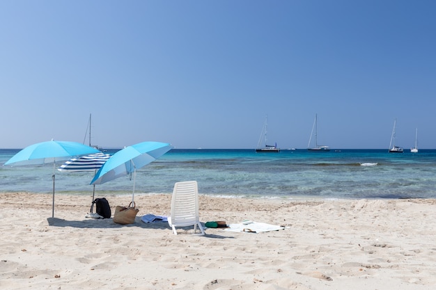 스페인 이비자(Ibiza)의 하얀 모래 해변에 있는 청록색 바다와 비치 파라솔