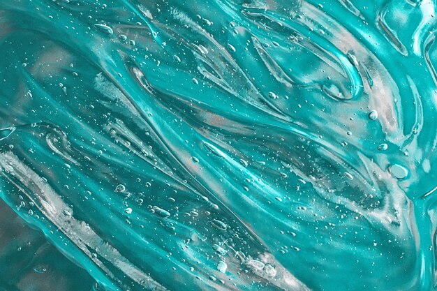 Turquoise waved serum with bubbles on the green backgroundCosmetics smear of aloe vera or gel