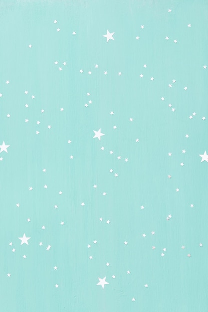 Turquoise wooden background with small shinny silver stars.