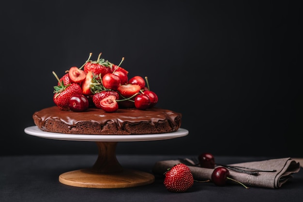 Tuscan chocolate cake with strawberries and cherries on dark background