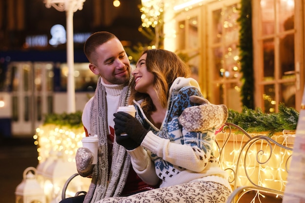 Tussen kerstversieringen romantisch koppel genietend van warme dranken terwijl ze een date hebben.