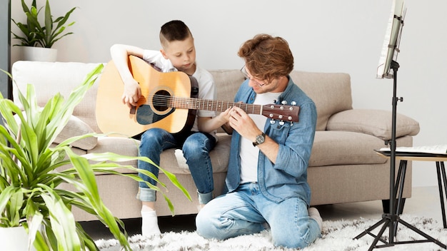 Tutor and boy learning how to play guitar long shot