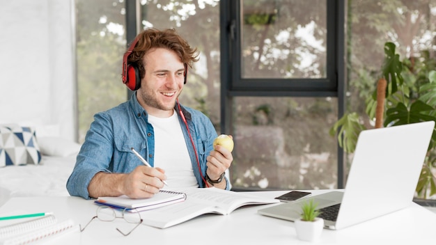 tutor at home holding an apple and smiles