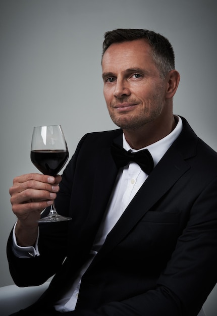 Tuxedo rode wijn en man portret met alcohol in een pak stijlvol gevoel met een luxe drankje grijze achtergrond geïsoleerd en studio met een modelagent of acteur met een glas rijk persoon met mockup