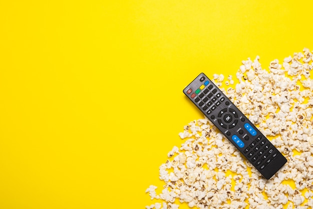 Tv-afstandsbediening, tv-tuner of audiosysteem en popcorn op geel