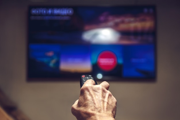 Photo tv remote control in the hands of an elderly man