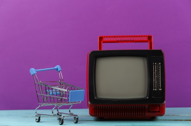 Tv supermarkt. Winkelwagentje met retro tv op paarse achtergrond