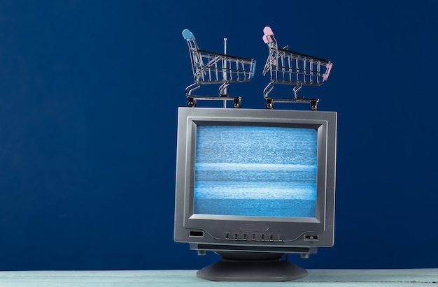 TV winkel. Antenne ouderwetse retro tv met mini supermarktkarretje op klassiek blauw