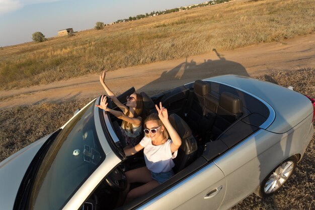 Twee aantrekkelijke jonge vrouwen in een cabriolet auto