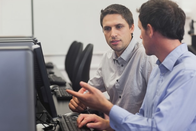 Foto twee aantrekkelijke mannen die in computerklasse spreken