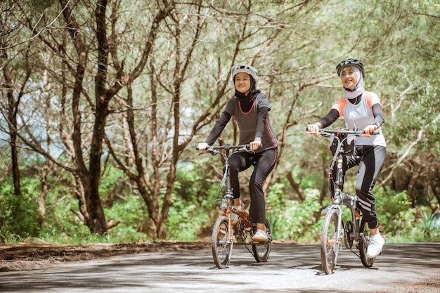 Twee aantrekkelijke moslimvrouwen genieten van samen fietsen op de weg