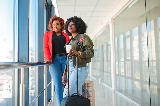 Twee afrikaanse meisjes met koffers op de luchthaven