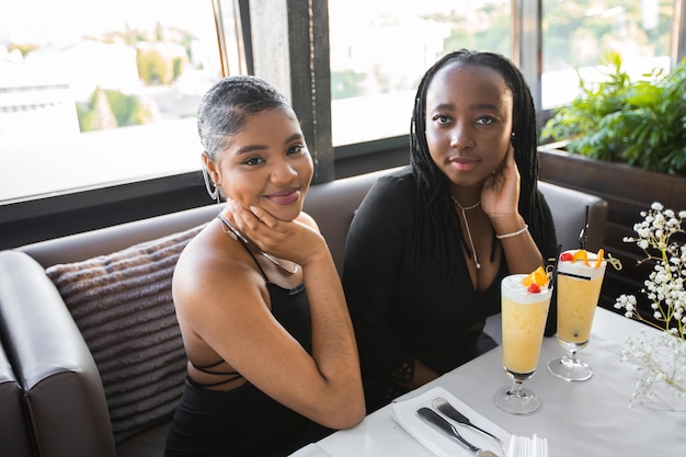 twee Afrikaanse vriendinnen in een restaurant met een drankje op een evenement