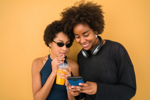 Twee Afro-vrienden met behulp van hun mobiele telefoon.