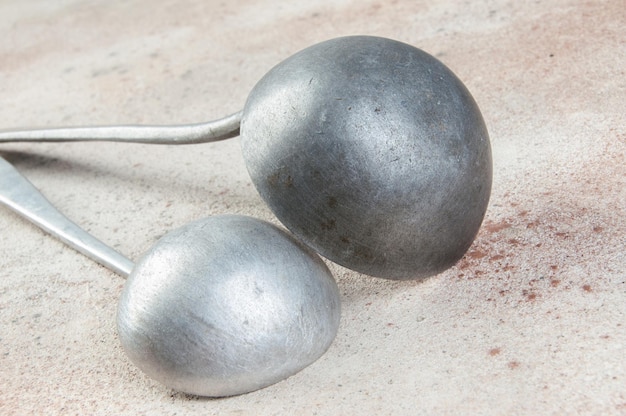 Twee aluminium pollepels. Vintage metalen keukengerei op betonnen ondergrond. Props voor voedselfotografie