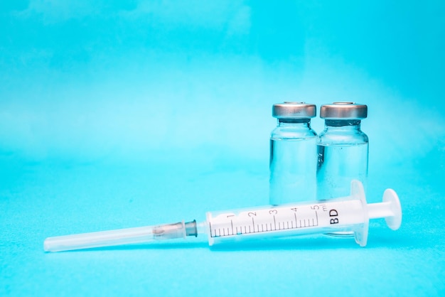 Twee ampullen vaccin met een spuit op een blauwe achtergrond Vaccinatiefoto's