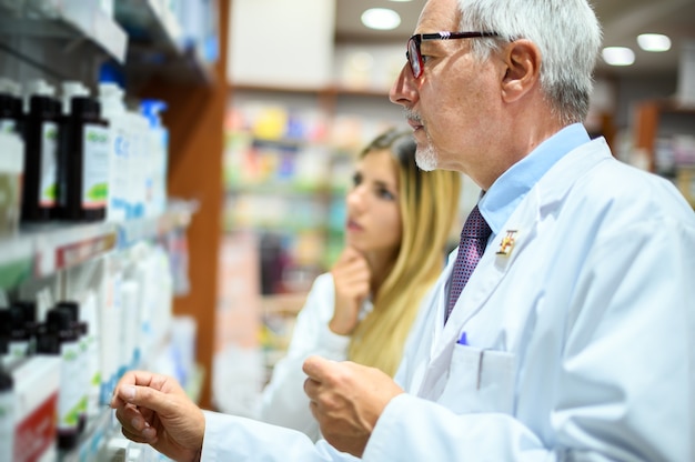 Twee apothekers, man en vrouw, op zoek naar een product op een plank