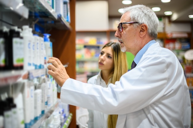 Twee apothekers, man en vrouw, op zoek naar een product op een plank