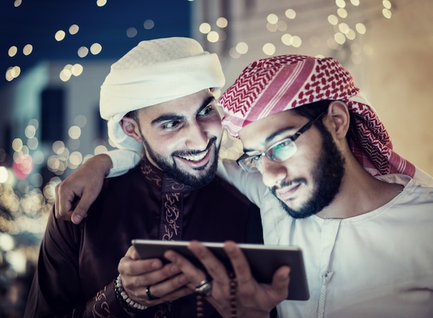 Twee arabische mannen met tablet in de stad 's nachts