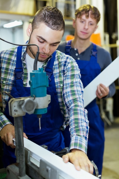 Twee arbeiders die aan een machine werken