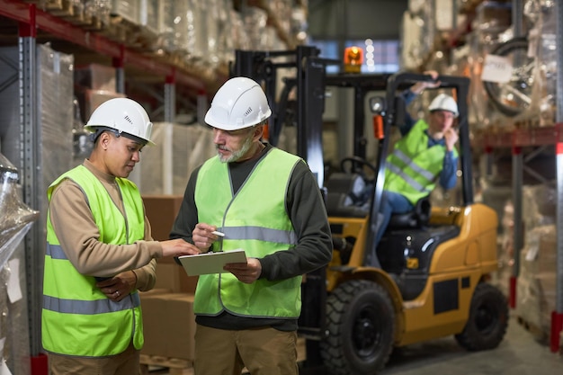 Twee arbeiders die inspectie in het klembord van de pakhuisholding doen