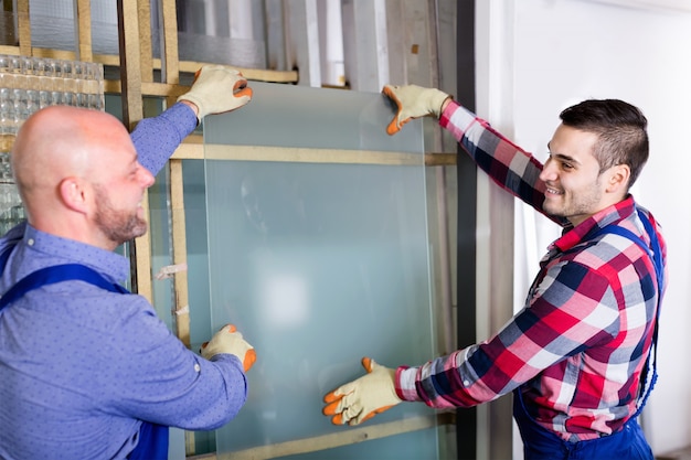 Twee arbeiders die met glas werken