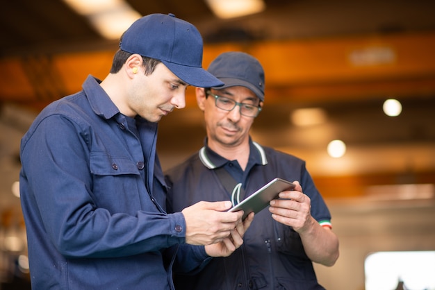 Twee arbeiders met behulp van een tablet in een moderne fabriek