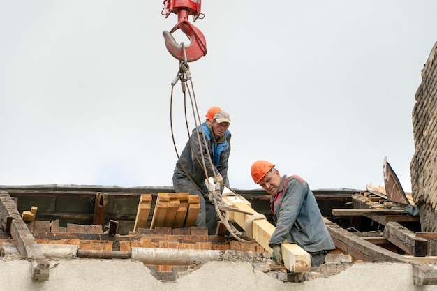 Twee arbeiders repareren het dak van een oud gebouw Reparatie van de dakvervanging van plafonds en houten balken installatie van nieuwe rode tegels