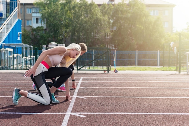 Twee atleet jonge vrouw loper aan de start in het stadion buiten