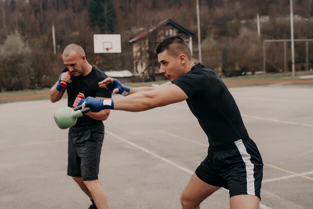 Twee atleet werktraining met kettlebell en dumbbells