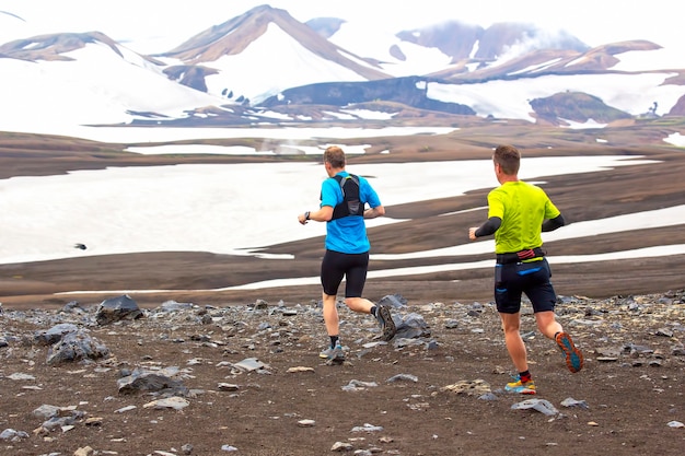 Twee atleten lopen een bergmarathon in het besneeuwde terrein van Landmannalaugar